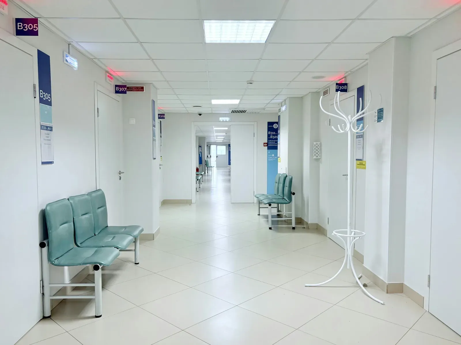 Leerer Krankenhausflur mit Sitzbänken und Zimmertüren