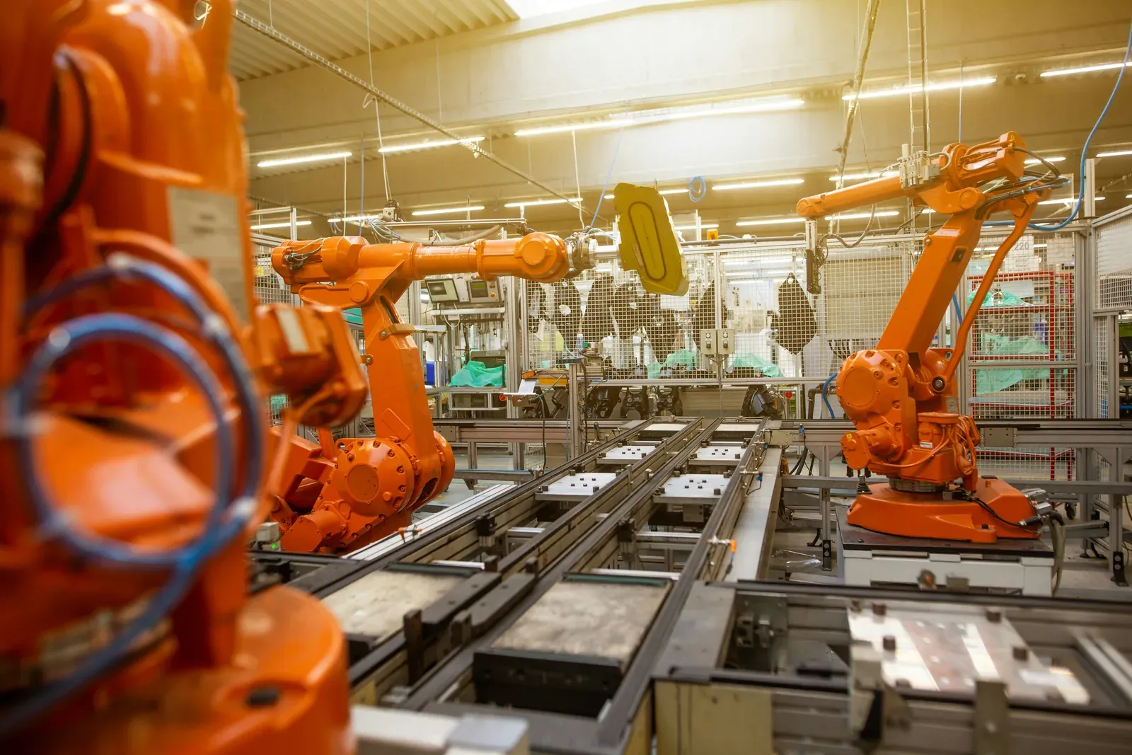 Orange Roboterarme an einer Fertigungslinie in einer Werkshalle