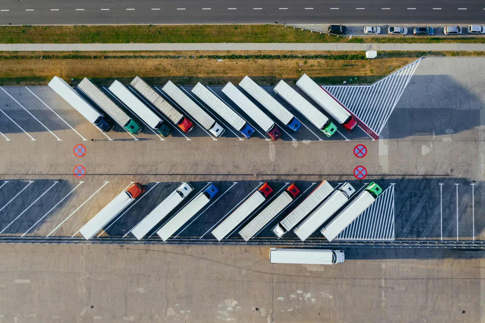 Luftaufnahme eines Lkw-Rastplatzes mit Sattelzügen in zwei Reihen