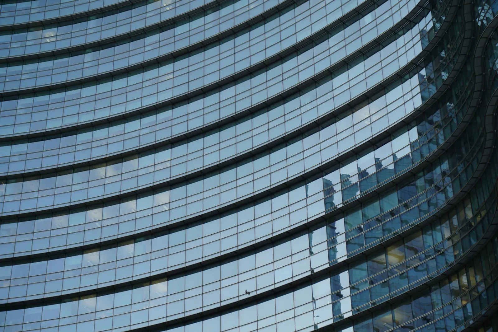 Gewölbte Glasfassade eines Bürohochhauses mit umlaufenden Bändern